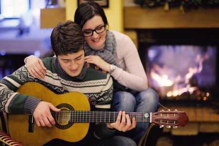 happy Young romantic couple sitting on sofa in front of fireplace at winter season in home
