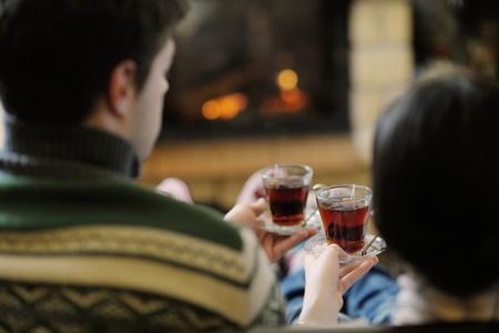 happy Young romantic couple sitting on sofa in front of fireplace at winter season in homeの写真素材
