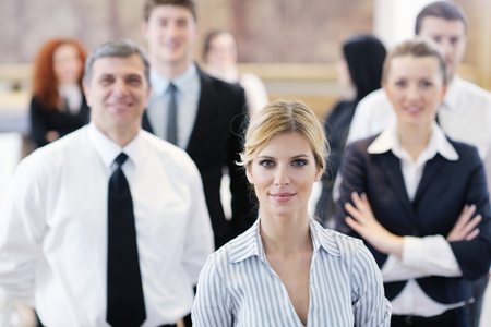 business woman standing with her staff in background at modern bright office conference roomの写真素材