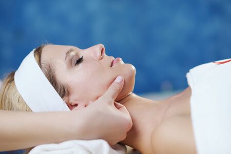 Beautiful young woman in spaand wellness. Face back and  stone massageの写真素材