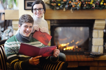 happy Young romantic couple and relaxing sofa in front of fireplace at winter season in homeの写真素材