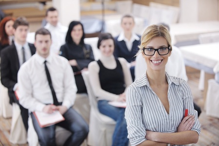 business woman standing with her staff in background at modern bright office conference roomの写真素材