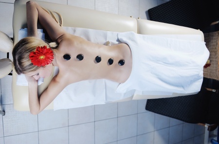 Beautiful young woman in spaand wellness. Face back and  stone massageの写真素材