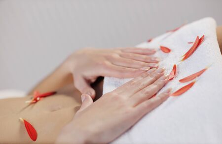 Beautiful young woman in spaand wellness. Face back and  stone massageの写真素材