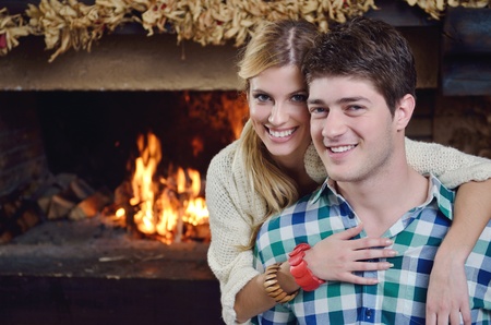 happy Young romantic couple and relaxing sofa in front of fireplace at winter season in homeの写真素材