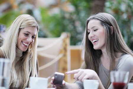 very cute smiling women drinking a coffee sitting inside in cafe restaurantの写真素材