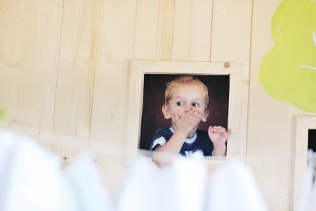 happy cute child in a wooden window at playgroundの写真素材