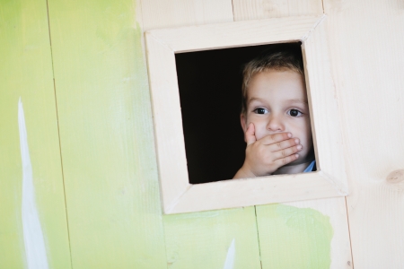 happy cute child in a wooden window at playgroundの写真素材