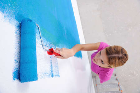 happy young couple paint in green and blue color white wall of their new home
