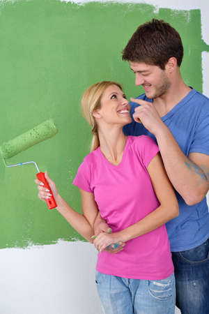 happy young couple paint in green and blue color white wall of their new homeの写真素材