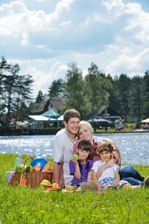 Happy young  family playing together with kids and eat healthy food  in a picnic outdoorsの写真素材