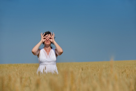Young woman standing jumping and running  on a wheat field with blue sky the background at summer day representing healthy life and agriculture conceptの写真素材