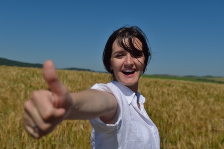 Young woman standing jumping and running  on a wheat field with blue sky the background at summer day representing healthy life and agriculture conceptの写真素材