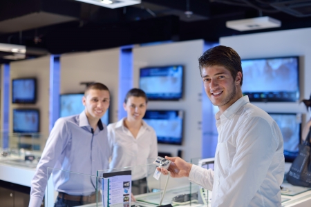 people in consumer electronics  retail store looking at latest laptop, television and photo camera...