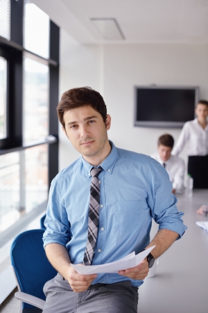Portrait of a handsome young  business man  on a meeting in offce with colleagues in backgroundの写真素材