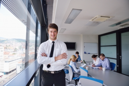 Portrait of a handsome young  business man  on a meeting in offce with colleagues in backgroundの写真素材