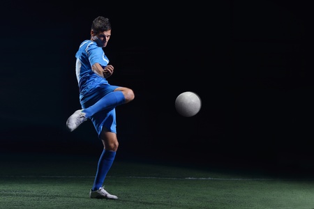 soccer player doing kick with ball on football stadium  field  isolated on black backgroundの写真素材