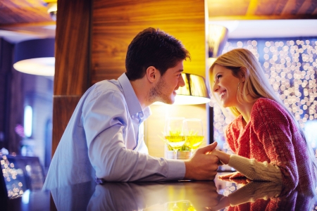 romantic evening date in restaurant  happy young couple with wine glass tea and cakeの写真素材