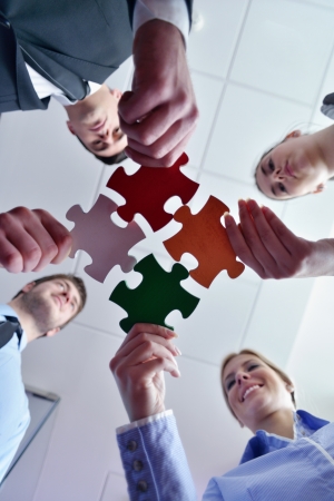 Group of business people assembling jigsaw puzzle and represent team support and help conceptの写真素材