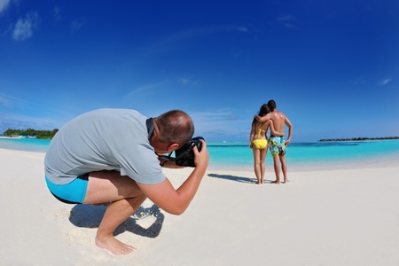 photographer taking photo of models couple on beautiful tropical beach at summerの写真素材