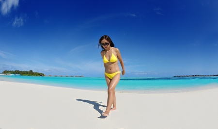 happy young beautiful asian woman relax on sand at tropical beach with cristal clear sea in backgroundの写真素材