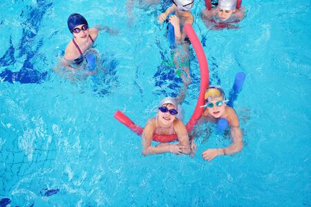 happy children kids group  at swimming pool class  learning to swim