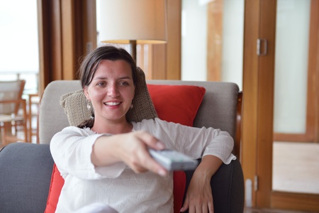 happy young woman relax at home on sofa in bright living room and watching tv