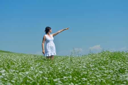 Young happy woman in green field with blue sky in backgroundの写真素材