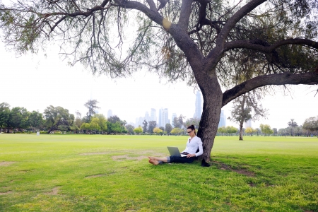 happy young student woman with laptop in city park studyの写真素材