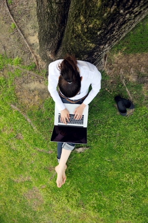 happy young student woman with laptop in city park studyの写真素材