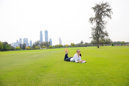 happy young student woman with laptop in city park studyの写真素材