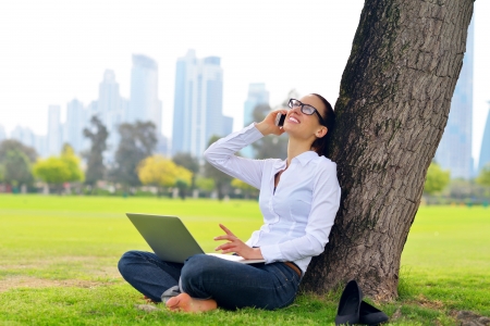 happy young student woman with laptop in city park studyの写真素材