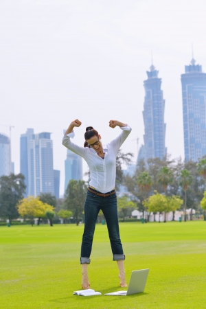 happy young student woman with laptop in city park studyの写真素材