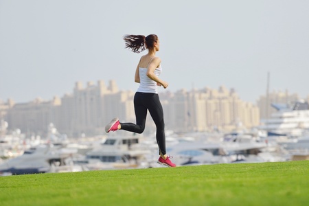 Running in city park. Woman runner outside jogging at morning with Dubai urban scene in backgroundの写真素材