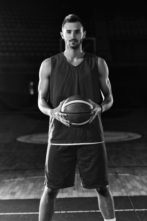 Basketball player portrait  on basketball court holding ball with black isolated backgroundの写真素材