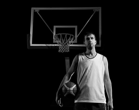 Basketball player portrait  on basketball court holding ball with black isolated backgroundの写真素材