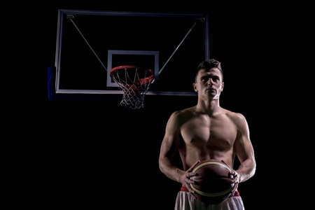 Basketball player portrait  on basketball court holding ball with black isolated backgroundの写真素材