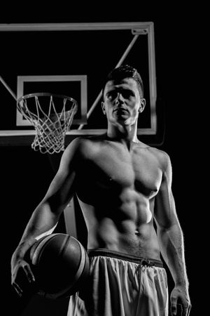 Basketball player portrait  on basketball court holding ball with black isolated backgroundの写真素材