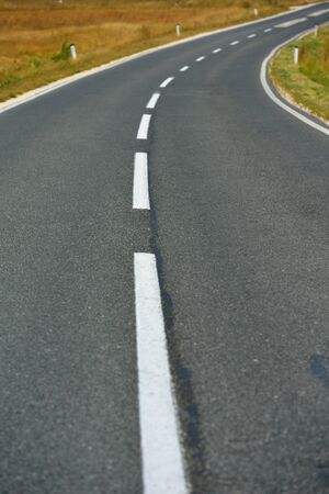 asphalt road through the green field and clouds on blue sky in summer dayの写真素材