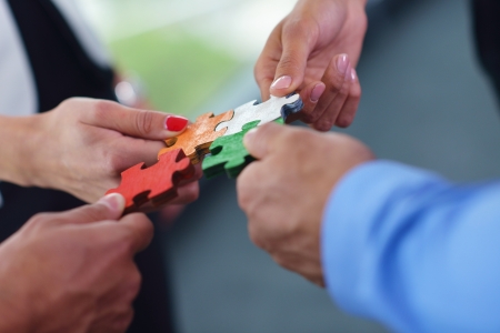 Group of business people assembling jigsaw puzzle and represent team support and help conceptの写真素材