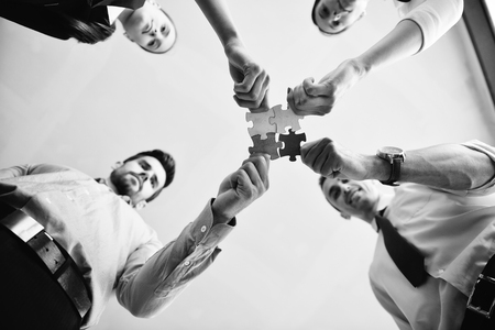 Group of business people assembling jigsaw puzzle and represent team support and help conceptの写真素材