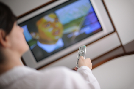happy young woman relax at home on sofa in bright living room and watching tvの写真素材