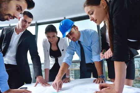 business people group on meeting and presentation  in bright modern office with construction engineer architect and worker looking building model and blueprint  plansの写真素材