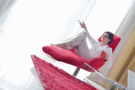 happy young woman relax at home on sofa in bright living room and watching tvの写真素材