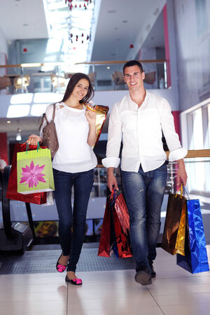 happy young couple with bags in shopping centre mallのeditorial素材