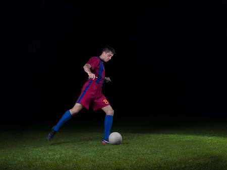soccer player doing kick with ball on football stadium  field  isolated on black backgroundの写真素材