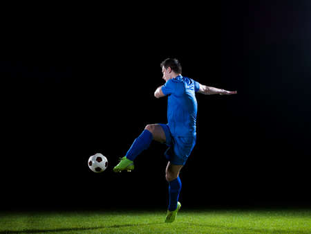 soccer player doing kick with ball on football stadium  field  isolated on black backgroundの写真素材