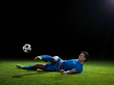 soccer player doing kick with ball on football stadium  field  isolated on black backgroundの写真素材