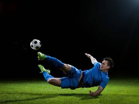 soccer player doing kick with ball on football stadium  field  isolated on black backgroundの写真素材