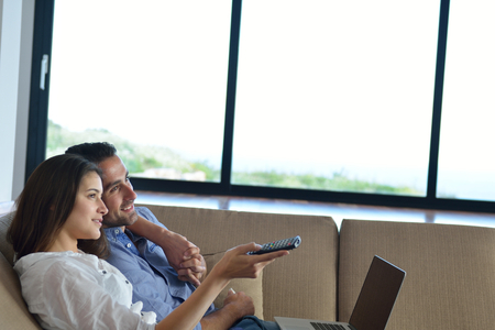Couple on sofa with TV remoteの写真素材